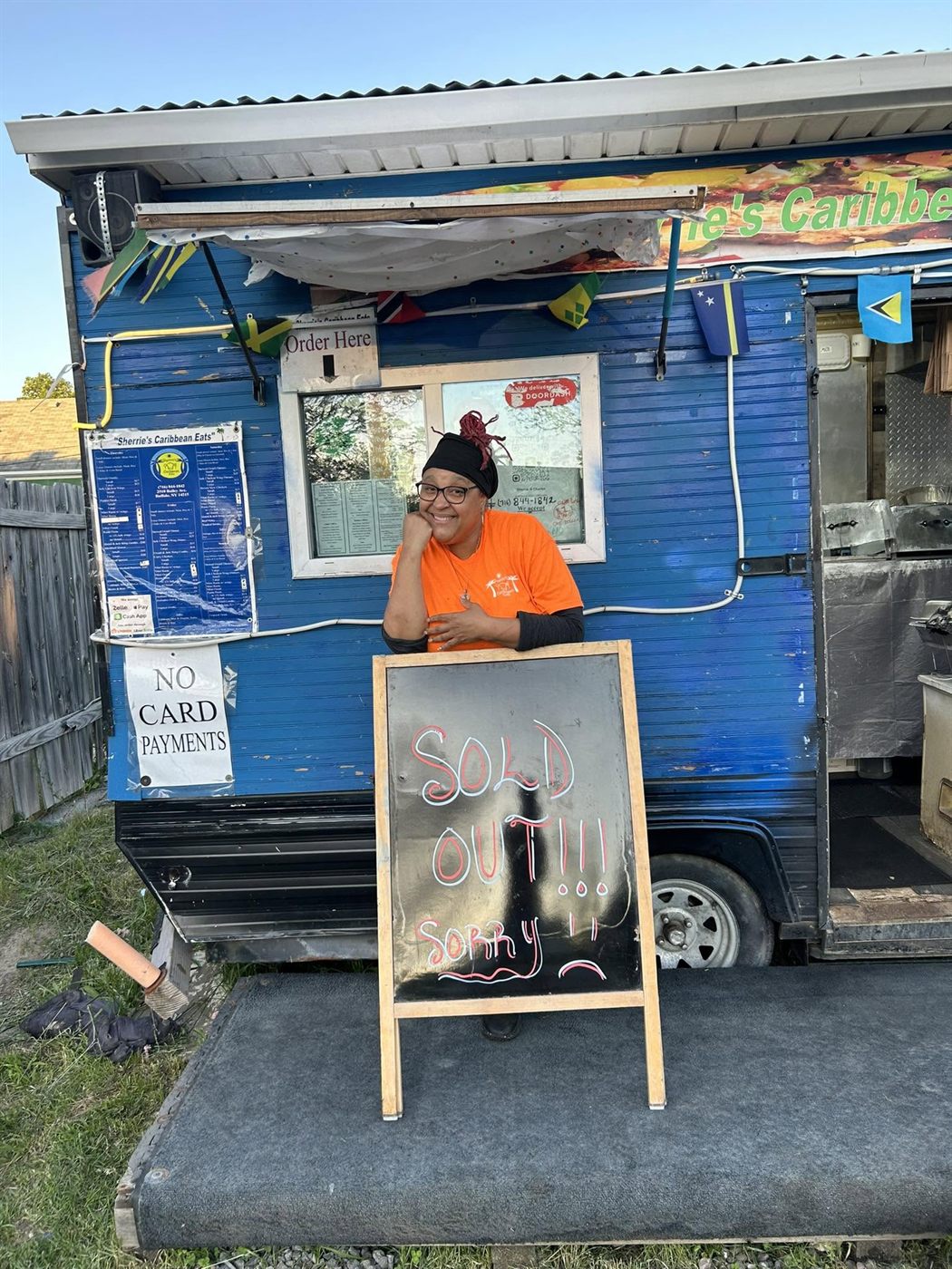 Sherrie by her food truck next to a hand lettered Sold Out sign